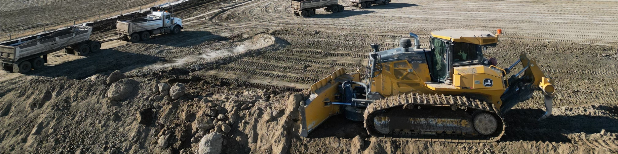Dozer cleaning up hill with truck trailer combo units in background