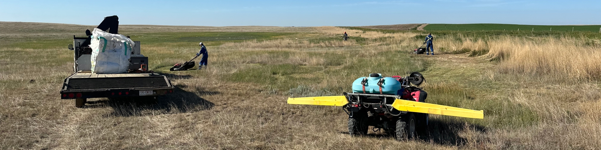 Crew with mowers and a sprayer on a quad within a field