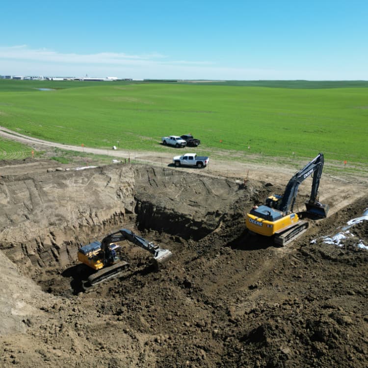 romers excavator digging inside hole with supporting team around