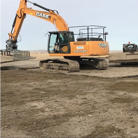 Excavator with grapple attachment moving mat.