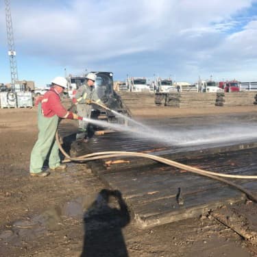 Cew spraying mat with water to clean them off