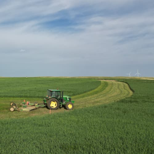 Tractor pulling mower around a bend in the field.