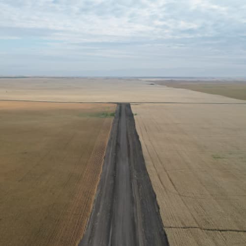 Completed gravel road with fields on either side.